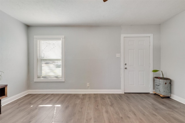 interior space featuring a textured ceiling, light wood finished floors, and baseboards