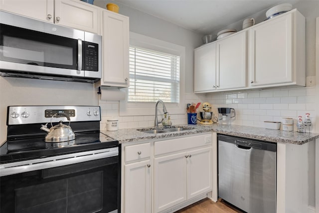 kitchen featuring appliances with stainless steel finishes, white cabinets, a sink, and tasteful backsplash