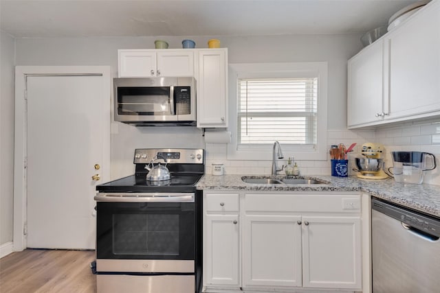 kitchen featuring white cabinets, tasteful backsplash, stainless steel appliances, and a sink