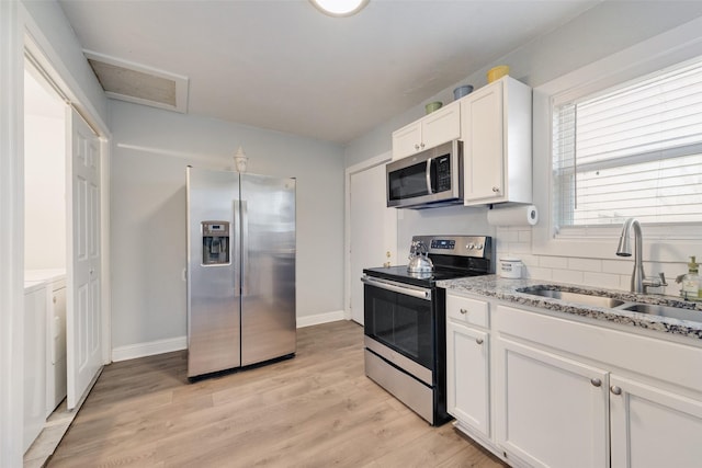 kitchen featuring white cabinetry, stainless steel appliances, a sink, and independent washer and dryer