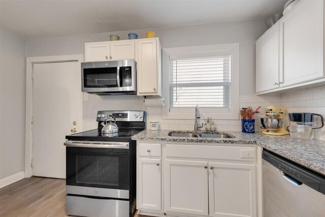 kitchen with white cabinetry, appliances with stainless steel finishes, backsplash, and a sink