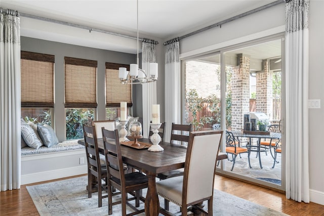 dining area featuring a notable chandelier, baseboards, and wood finished floors