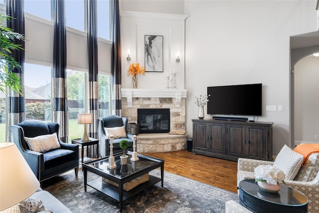 living room with arched walkways, a fireplace, and wood finished floors