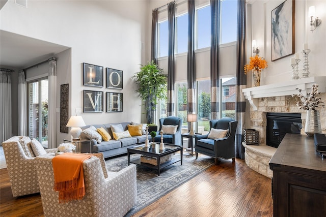 living area featuring dark wood-style floors, a fireplace, and a towering ceiling