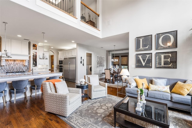 living area with washer / clothes dryer, dark wood finished floors, visible vents, and a notable chandelier