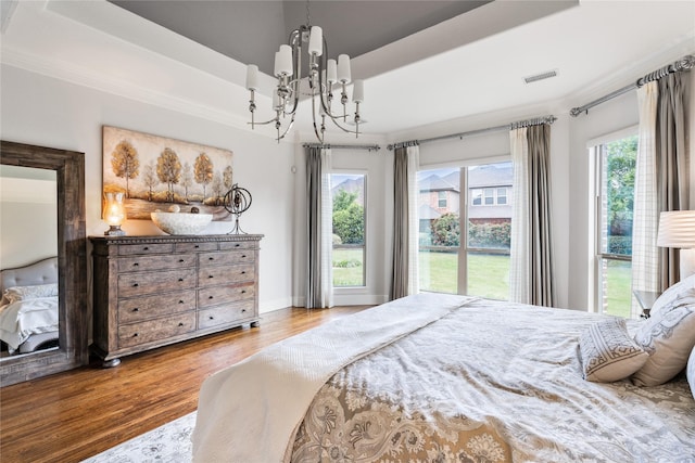 bedroom featuring crown molding, a notable chandelier, a raised ceiling, visible vents, and wood finished floors