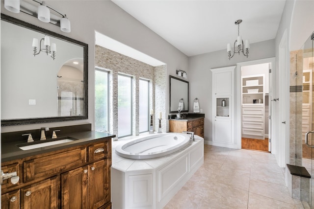 bathroom with a chandelier, tile patterned flooring, a sink, a bath, and a stall shower