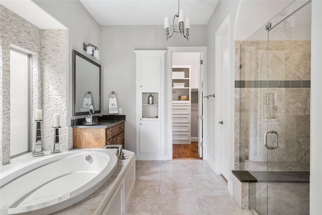 full bath featuring a spacious closet, an inviting chandelier, a shower stall, vanity, and a bath