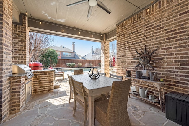 view of patio featuring an outdoor kitchen, ceiling fan, a grill, fence, and outdoor dining space