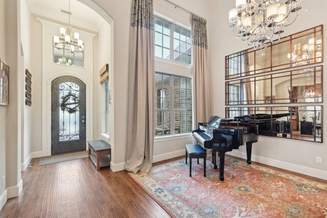 living area with arched walkways, a towering ceiling, baseboards, and wood finished floors