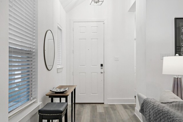 entryway featuring vaulted ceiling, baseboards, and wood finished floors