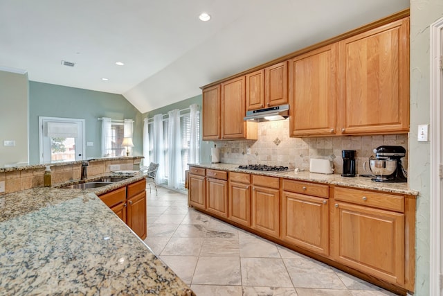 kitchen with backsplash, under cabinet range hood, lofted ceiling, stainless steel gas stovetop, and a sink