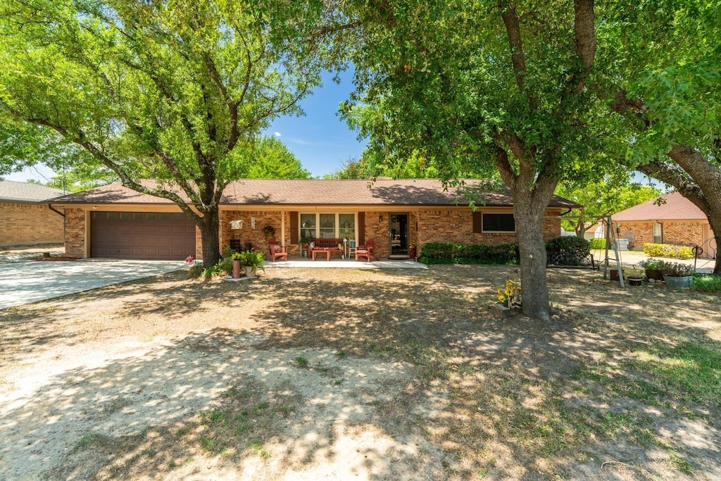 ranch-style house featuring a garage, driveway, and brick siding