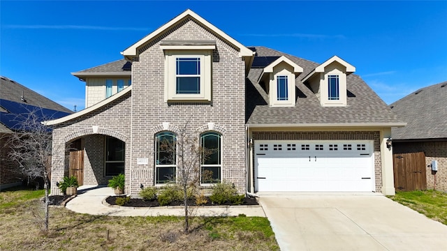 view of front of house featuring roof with shingles, driveway, brick siding, and an attached garage