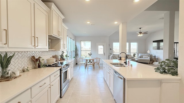 kitchen with light tile patterned flooring, stainless steel appliances, a sink, white cabinetry, and tasteful backsplash