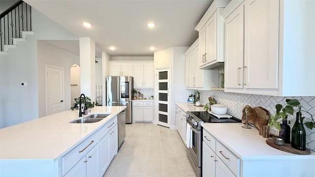 kitchen with a sink, white cabinetry, light countertops, appliances with stainless steel finishes, and decorative backsplash