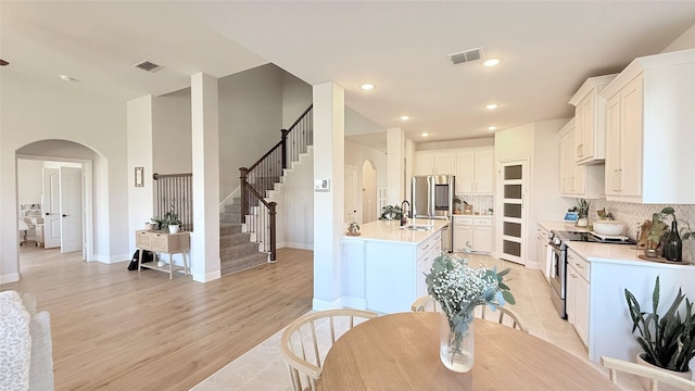 kitchen with stainless steel electric range oven, light countertops, arched walkways, and visible vents