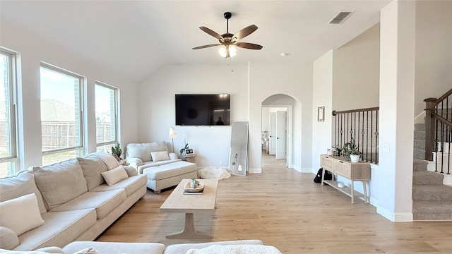 living area with arched walkways, visible vents, light wood-style flooring, stairway, and baseboards