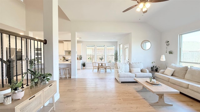 living room with light wood-style floors, ceiling fan, and vaulted ceiling