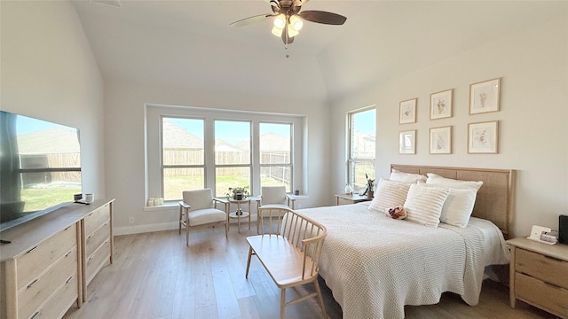 bedroom with lofted ceiling, multiple windows, light wood-style flooring, and baseboards