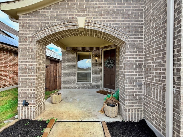 property entrance with a patio area, brick siding, and fence