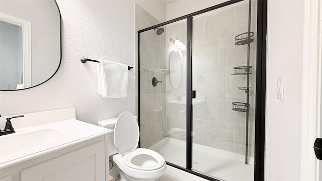 bathroom featuring a textured wall, a stall shower, vanity, and toilet