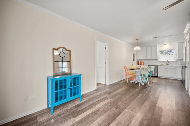 dining area with baseboards, crown molding, visible vents, and wood finished floors