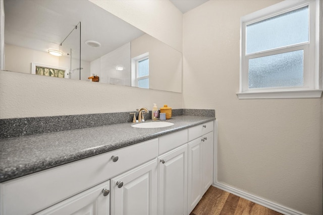 bathroom with baseboards, wood finished floors, and vanity