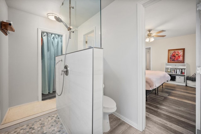 bathroom with tiled shower, wood finished floors, toilet, and a ceiling fan