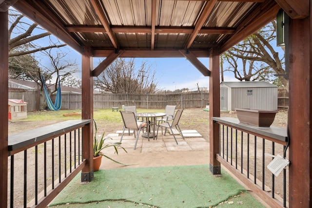 view of patio / terrace featuring outdoor dining space, a fenced backyard, an outdoor structure, and a storage shed