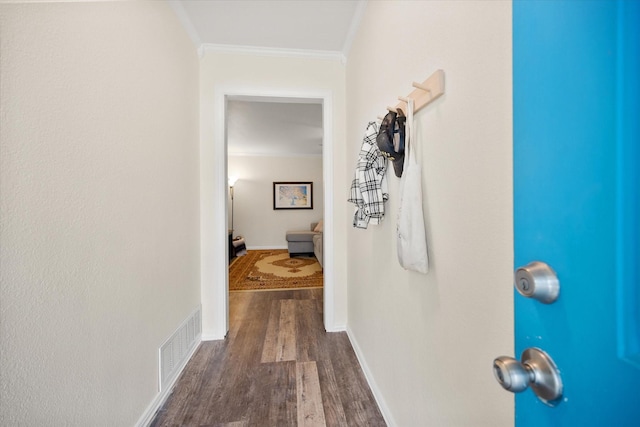 hallway with dark wood-style floors, visible vents, crown molding, and baseboards