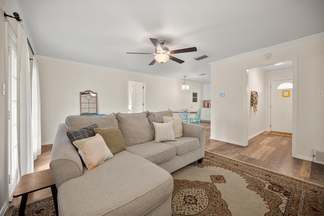 living room featuring visible vents, wood finished floors, and ornamental molding