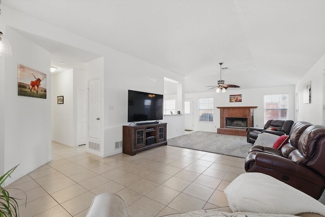 living room featuring light tile patterned floors, visible vents, a ceiling fan, vaulted ceiling, and a fireplace