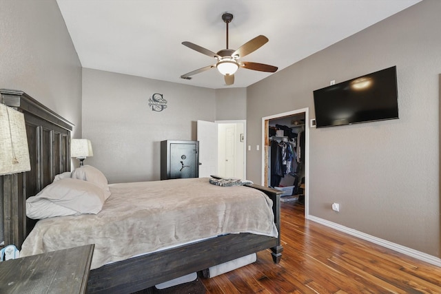 bedroom with ceiling fan, wood finished floors, baseboards, a spacious closet, and a closet