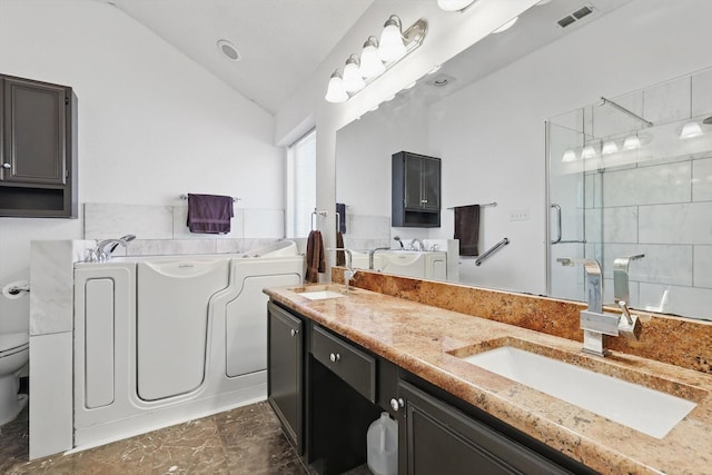 bathroom with a stall shower, visible vents, a garden tub, vaulted ceiling, and a sink