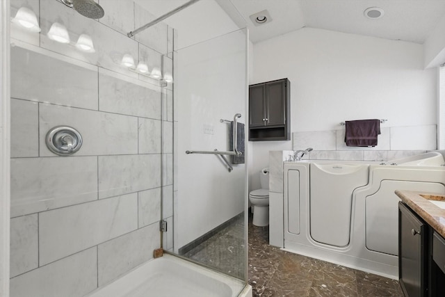 bathroom with a stall shower, toilet, washer / clothes dryer, vaulted ceiling, and vanity