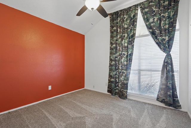 spare room featuring carpet floors, ceiling fan, baseboards, and vaulted ceiling