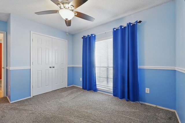 unfurnished bedroom with a textured ceiling, multiple windows, a closet, and carpet