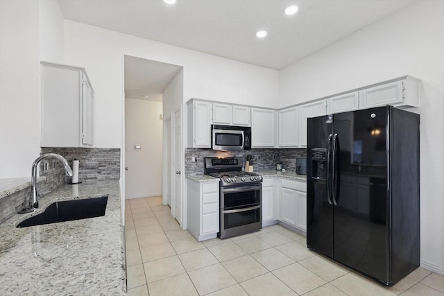 kitchen featuring light tile patterned floors, stainless steel appliances, a sink, and light stone countertops