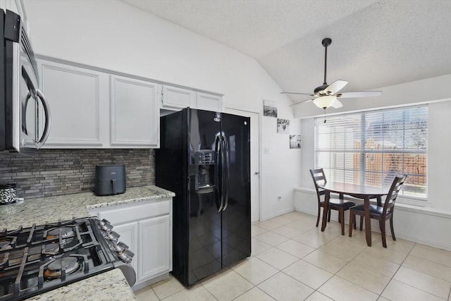 kitchen with tasteful backsplash, light stone counters, vaulted ceiling, black appliances, and light tile patterned flooring