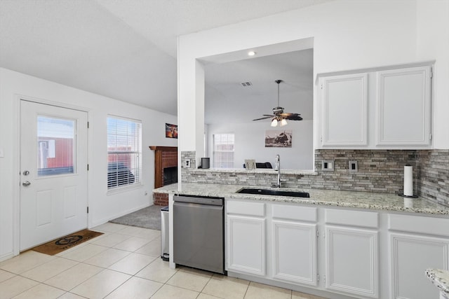 kitchen with tasteful backsplash, lofted ceiling, white cabinetry, a sink, and dishwasher