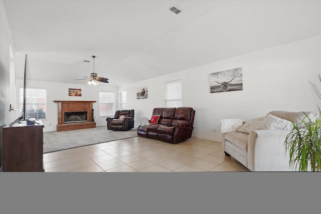 living area featuring light tile patterned floors, lofted ceiling, visible vents, a ceiling fan, and a brick fireplace