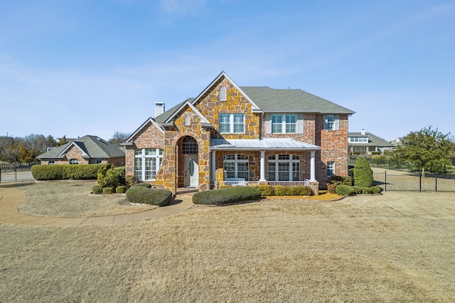 view of front of property featuring stone siding, brick siding, a chimney, and a front lawn