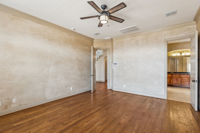 spare room with ornamental molding, light wood-type flooring, visible vents, and baseboards