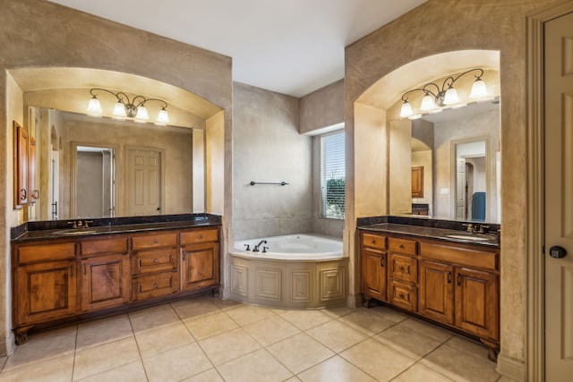 bathroom with a garden tub, tile patterned flooring, two vanities, and a sink