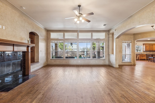 unfurnished living room with ceiling fan, visible vents, ornamental molding, and wood finished floors