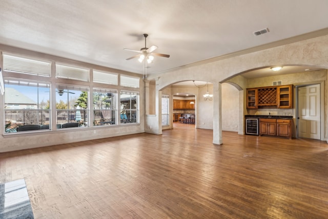 unfurnished living room featuring beverage cooler, visible vents, ceiling fan, and wood finished floors