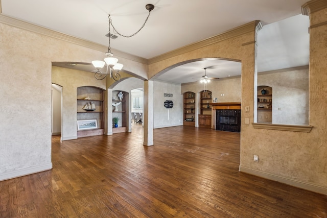 unfurnished living room with ceiling fan with notable chandelier, a fireplace, wood finished floors, baseboards, and built in features