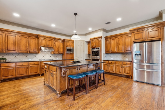 5805 Parker Village Dr, Parker, TX 75002 - kitchen with stainless steel appliances, brown cabinets, a kitchen island, under cabinet range hood, and ornamental molding