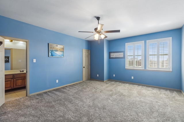 unfurnished bedroom featuring carpet floors, connected bathroom, baseboards, and a ceiling fan